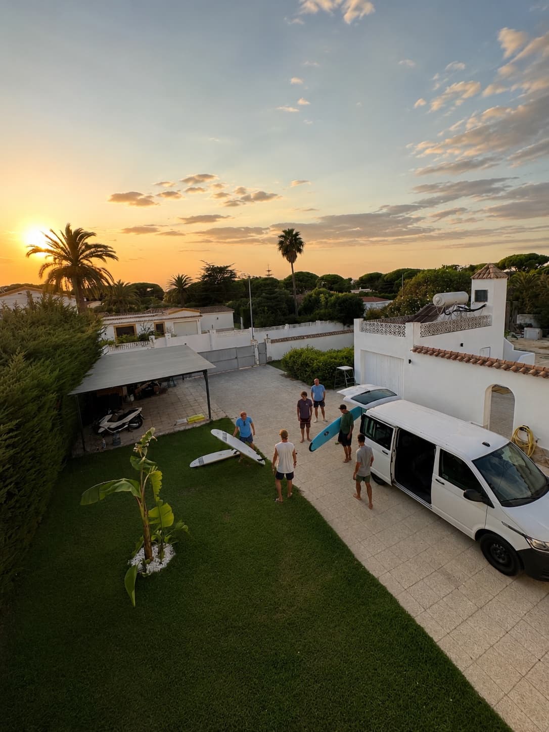 Sunset over the villa courtyard: surfboards on the grass, the van loaded, the group getting ready for the ocean